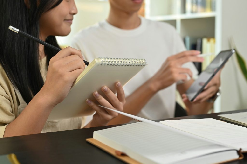 Tutor pointing at digital tablet, giving private educational lesson to focused teenage girl.