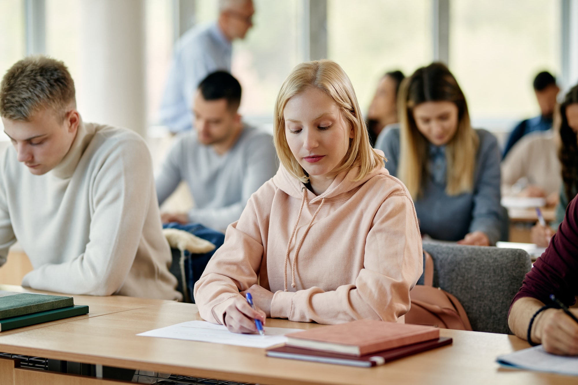 Young woman writing exam in lecture hall at the university.