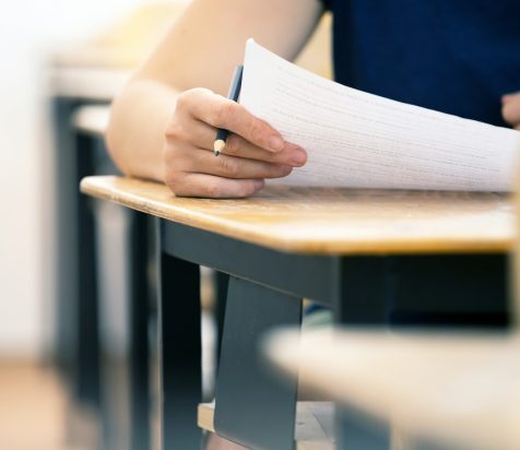 Student writing final exam in classroom.